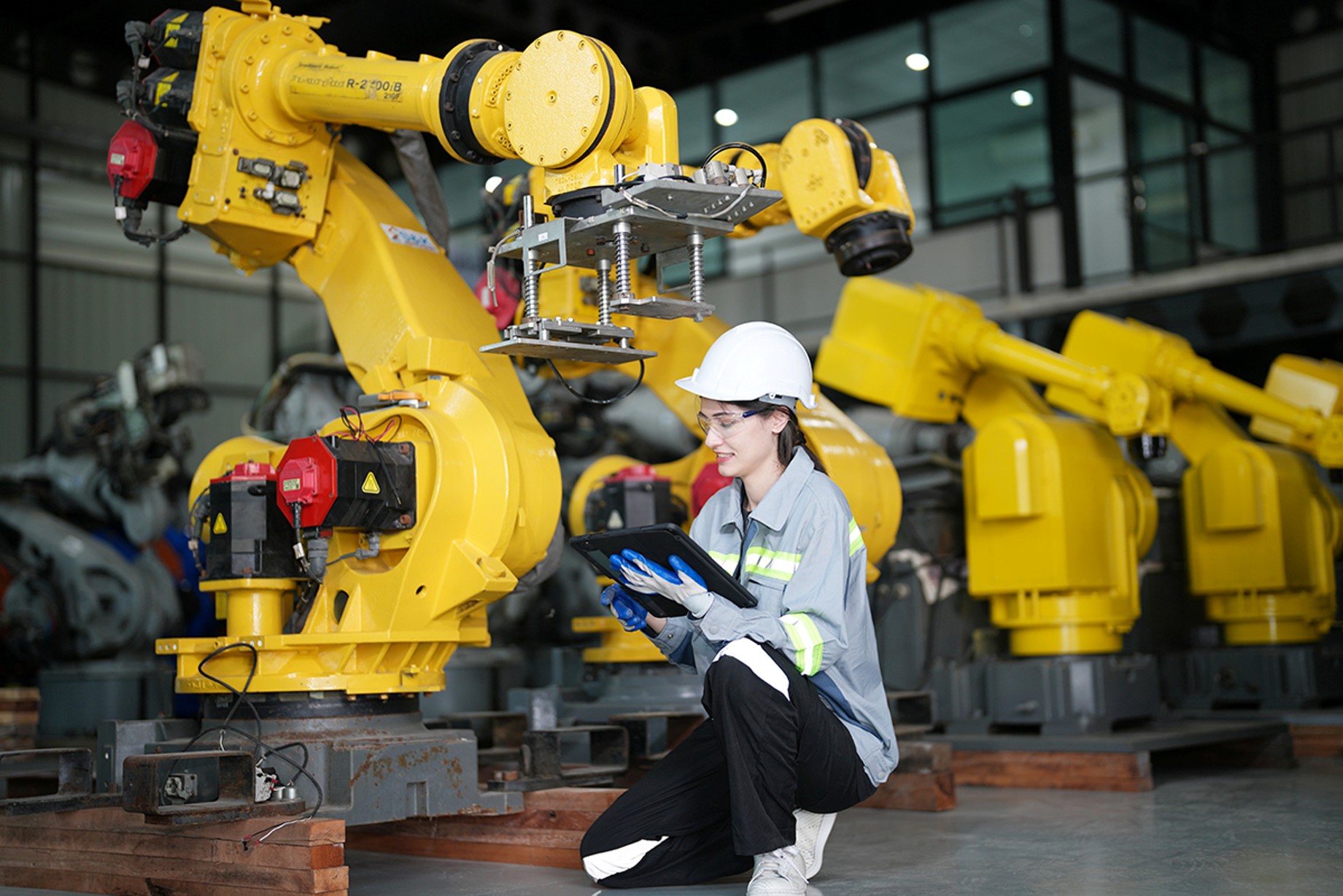 Ingeniera revisando brazos robóticos en planta